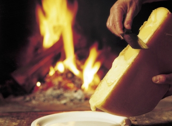Raclettekäse abschaben Geschmolzener Käse in Teller abstreifen